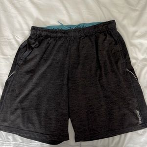 Mens Reebok athletic shorts in dark gray with inside teal waistband. 21.5” L.